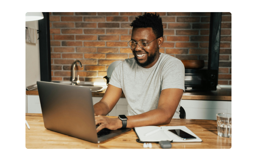 Smiling man working on a laptop in a modern kitchen, showing affiliate marketing and passive income to make money online.